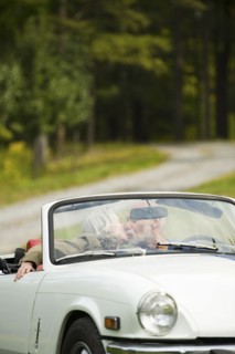 Older couple kissing in convertible on dirt road
