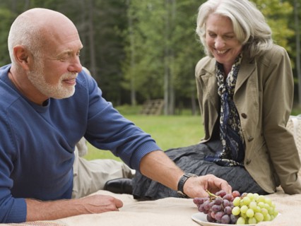 Older couple eating grapes at picnic in park