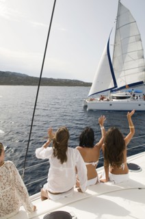 Women waving from sailboat on ocean