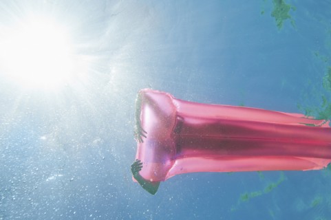 Underwater view of woman sunbathing on raft in ocean