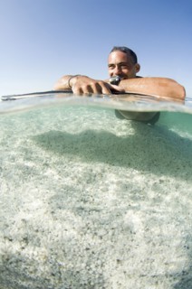 Close up of man laying on surfboard in ocean