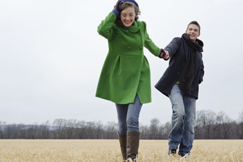 Caucasian couple walking in rural field