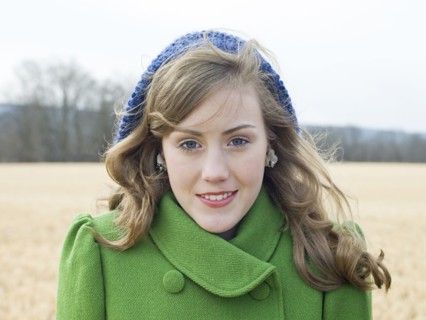 Caucasian woman wearing coat and hat in field