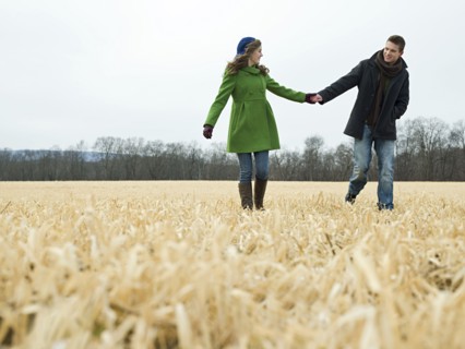 Caucasian couple holding hands in rural field