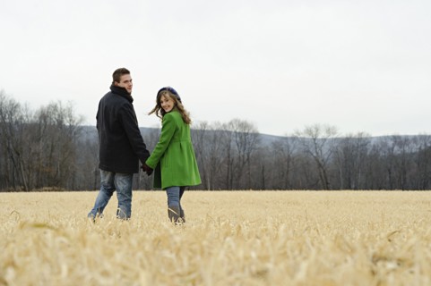 Caucasian couple walking in rural field