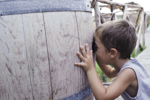 Caucasian boy peering into barrel