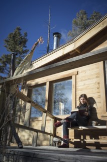 Caucasian woman reading book on cabin porch