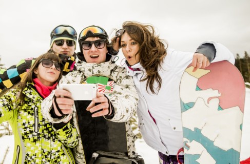 Caucasian friends with snowboard taking selfie