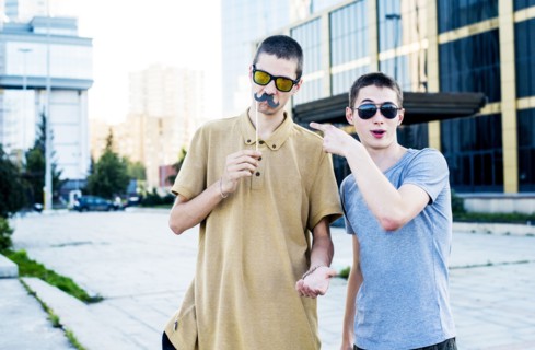 Caucasian men playing with fake mustaches in city