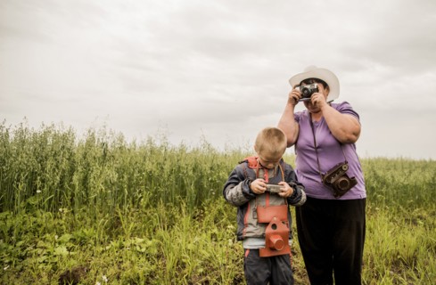 Caucasian mother and son taking photographs in rural field