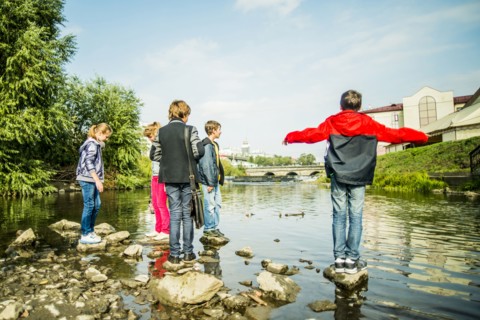 Caucasian children playing on rocks in river