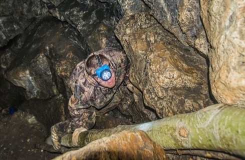 Caucasian climber exploring rock formation cave