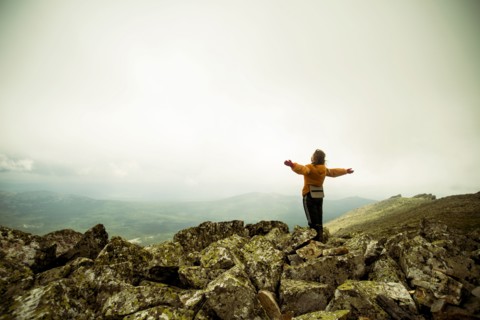 Caucasian hiker with arms outstretched on rocky hilltop