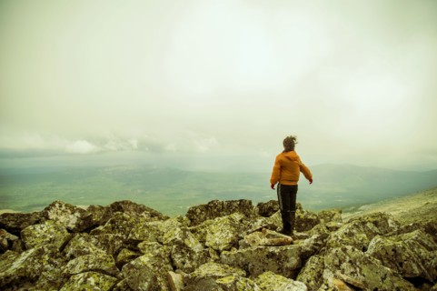 Caucasian hiker enjoying scenic view from rocky hilltop