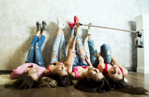 Caucasian women taking cell phone selfie on floor