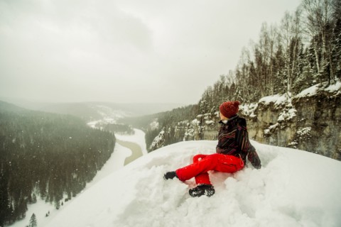 Caucasian hiker sitting on snowy hilltop