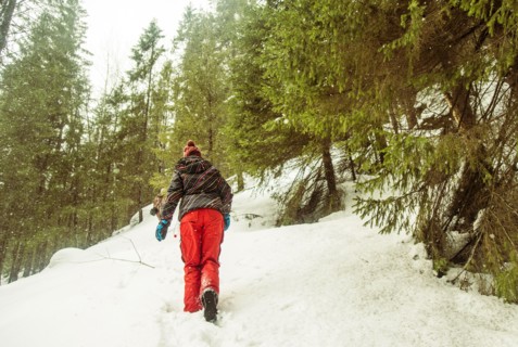 Caucasian hiker climbing snowy hillside