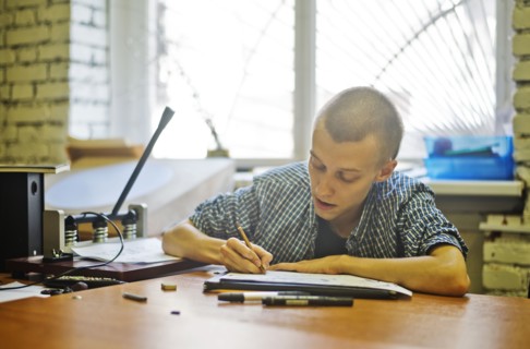 Caucasian artist drawing at studio desk