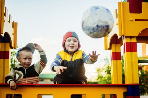 Caucasian boys throwing ball in playground