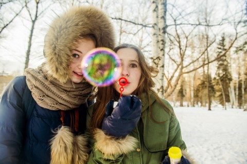 Caucasian women blowing bubbles in snowy field