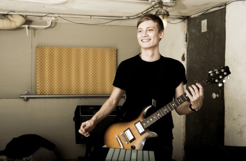 Caucasian man playing electric guitar in rock band