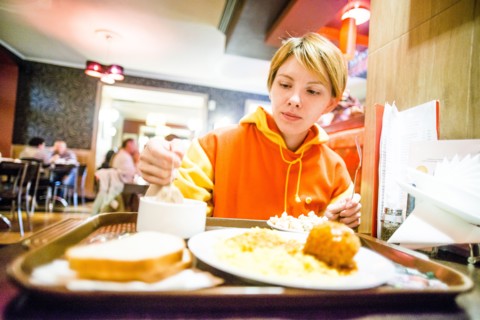 Caucasian woman eating breakfast in cafeteria