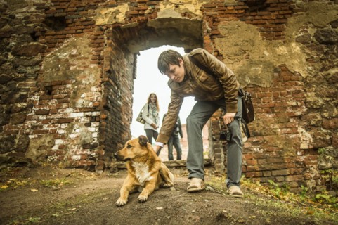 Caucasian man petting dog near ruins