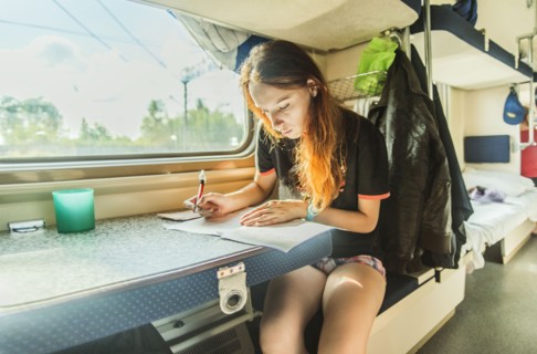 Caucasian girl writing on train