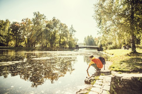 Caucasian woman dipping hand in park pond