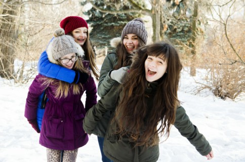 Caucasian girls playing in snowy field