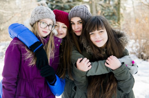 Caucasian girls hugging in snowy field