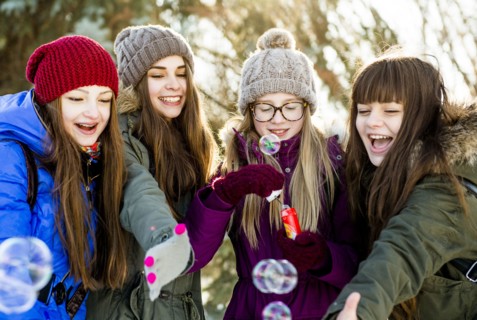 Caucasian girls blowing bubbles outdoors in winter