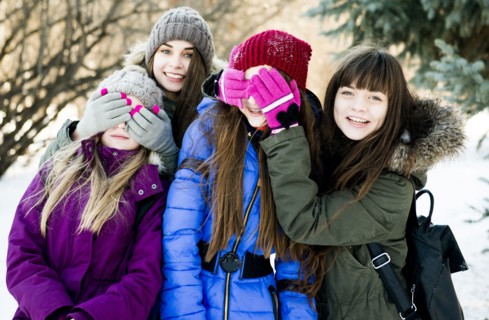 Caucasian girls playing in snowy field