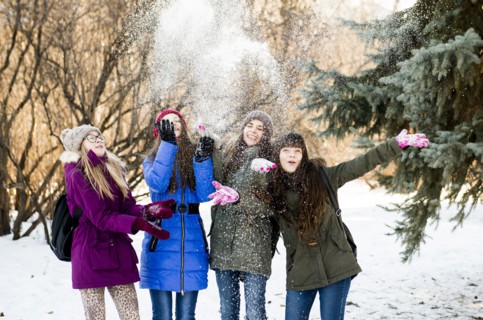 Caucasian girls throwing snow in field