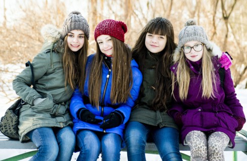 Caucasian girls smiling on bench in winter