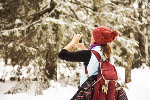 Caucasian woman photographing nature on snowy path