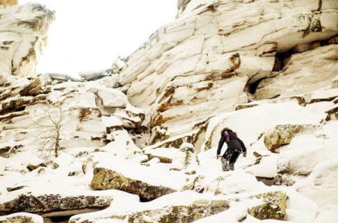 Caucasian hiker climbing snowy rock formations