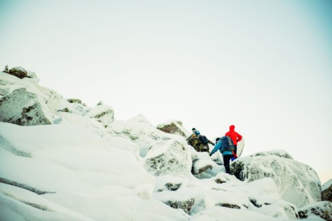 Caucasian hiker climbing snowy rock formations