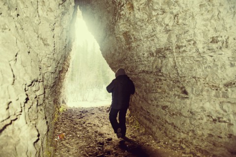 Caucasian hiker walking in rocky cave