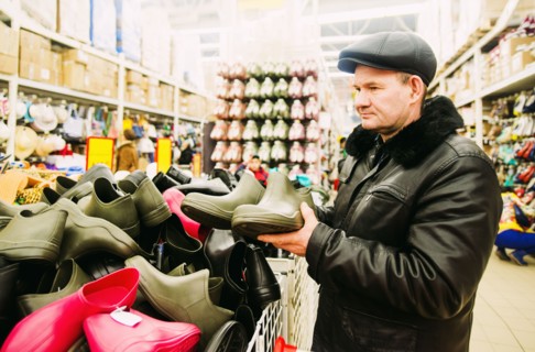 Caucasian man shopping for rain boots in store