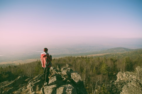 Caucasian hiker admiring view from remote rock formation
