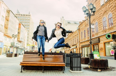 Women jumping for joy near bench