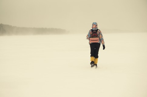 Caucasian hiker walking in snowy remote field
