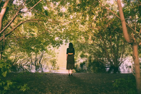 Caucasian woman standing under trees near river