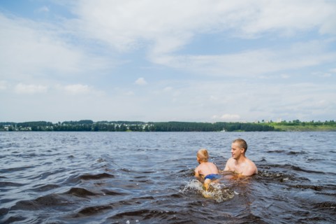 Caucasian father and son swimming in lake