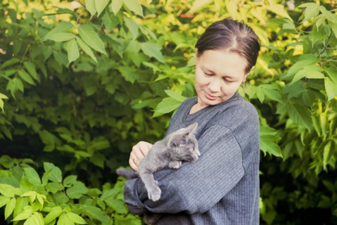 Caucasian woman petting cat in garden