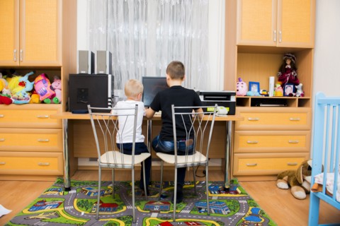 Caucasian brothers using computer in bedroom