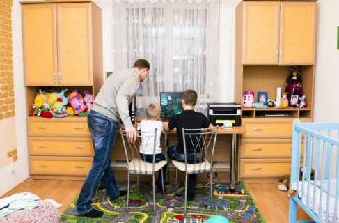 Caucasian father and sons using computer in bedroom