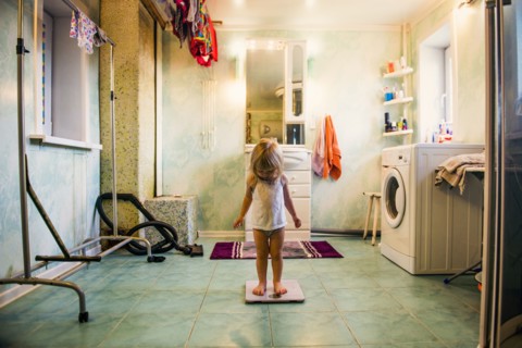 Caucasian girl standing on scale in bathroom
