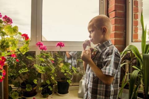 Caucasian boy drinking juice from mug by window